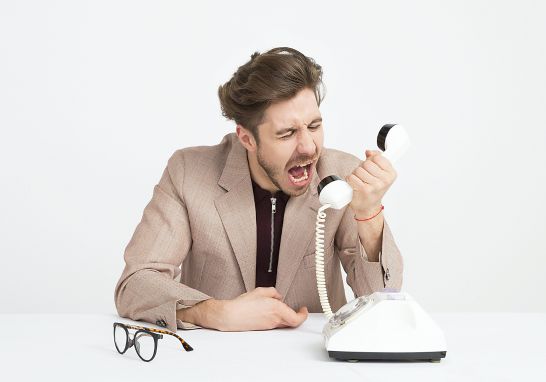 A man shouting at the telephone to represent customer relationship management